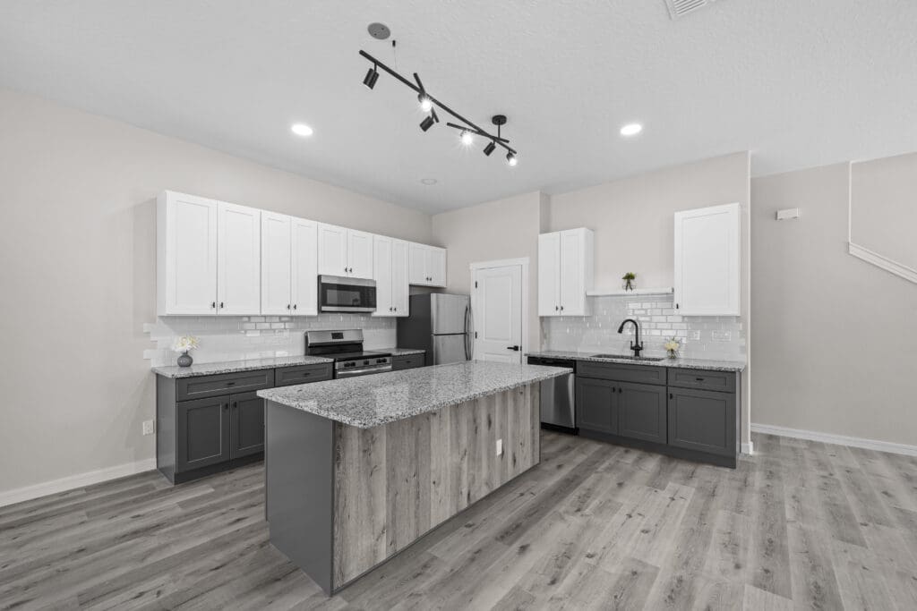 Gray kitchen island with white cabinets and track lighting