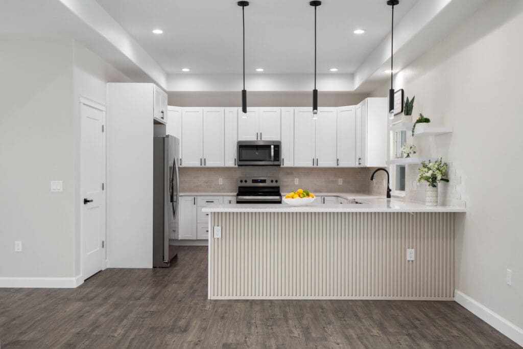 Front view of white kitchen with island and pendant lighting