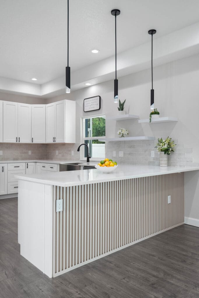 White kitchen island with vertical slat detail and pendant lights